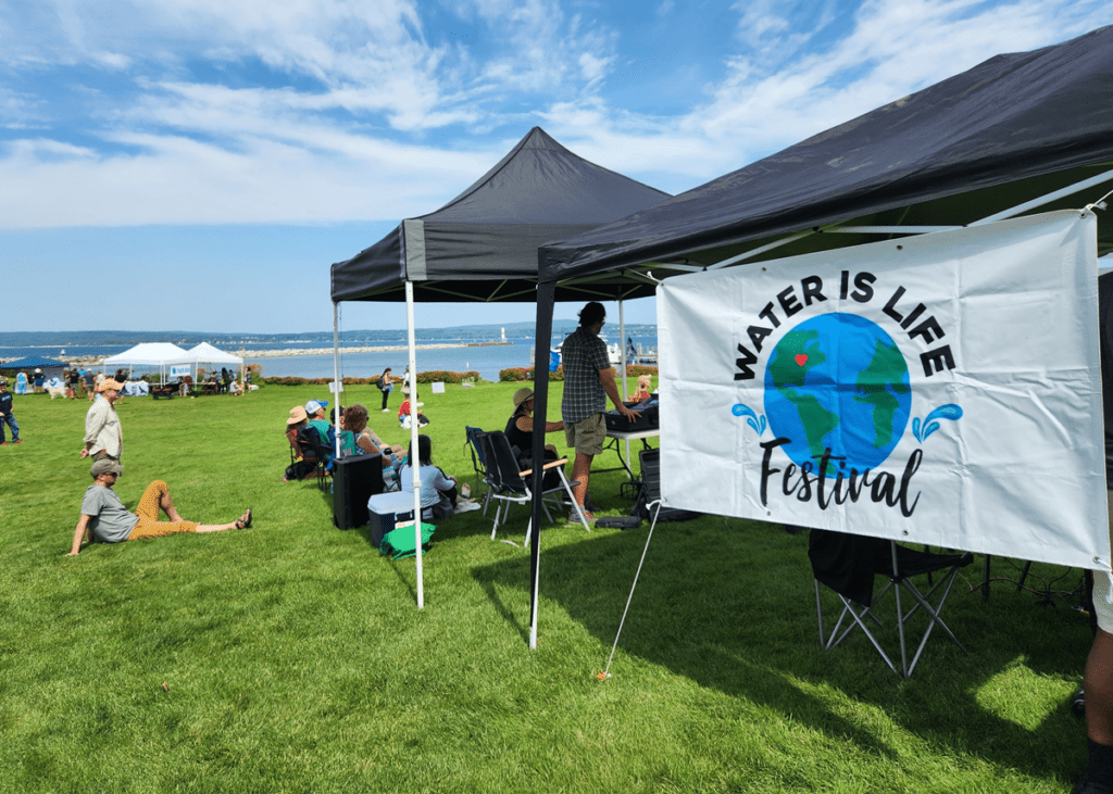 banner that reads "Water Is Life Festival" at a small event tent